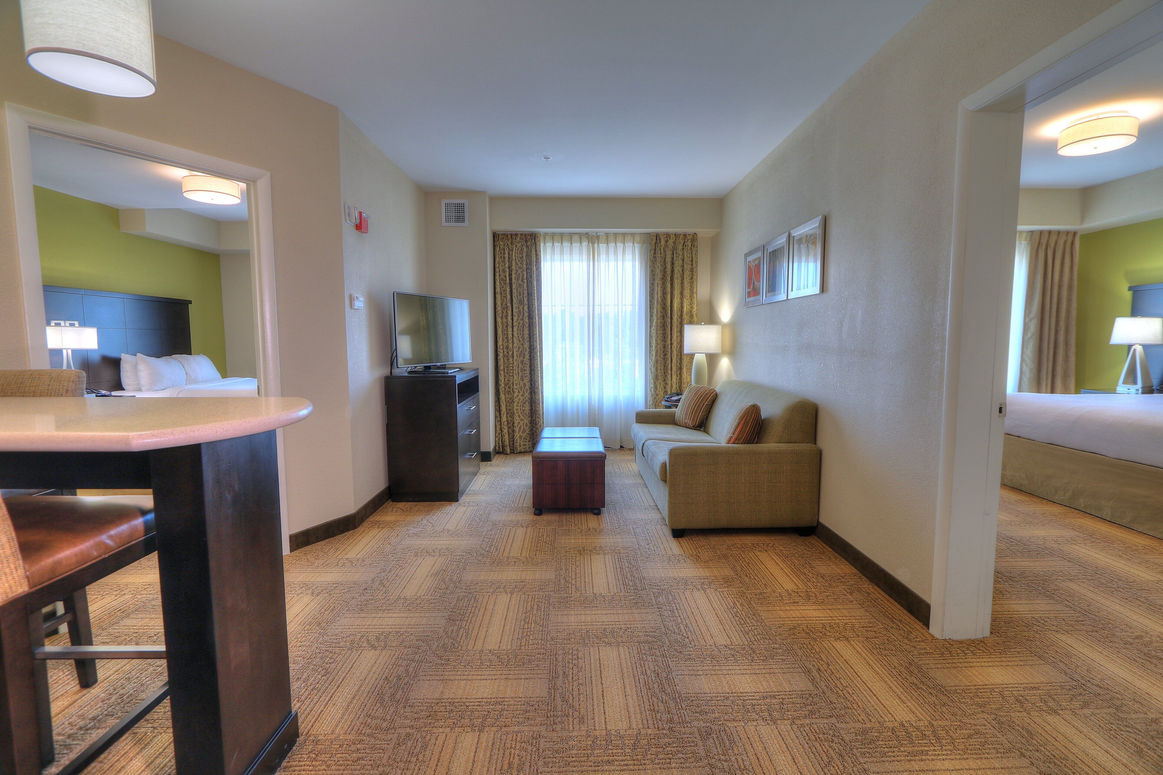 Een hotelkamer met een bank, een televisie, een bureau en een spiegel.