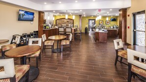 A spacious restaurant area with multiple dining tables and chairs, a kitchen counter, and a television mounted on the wall. - Staybridge Suites Knoxville-West by IHG (Farragut)