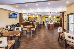 Un vaste espace restaurant comprenant plusieurs tables et chaises, un comptoir de cuisine et un téléviseur fixé au mur.