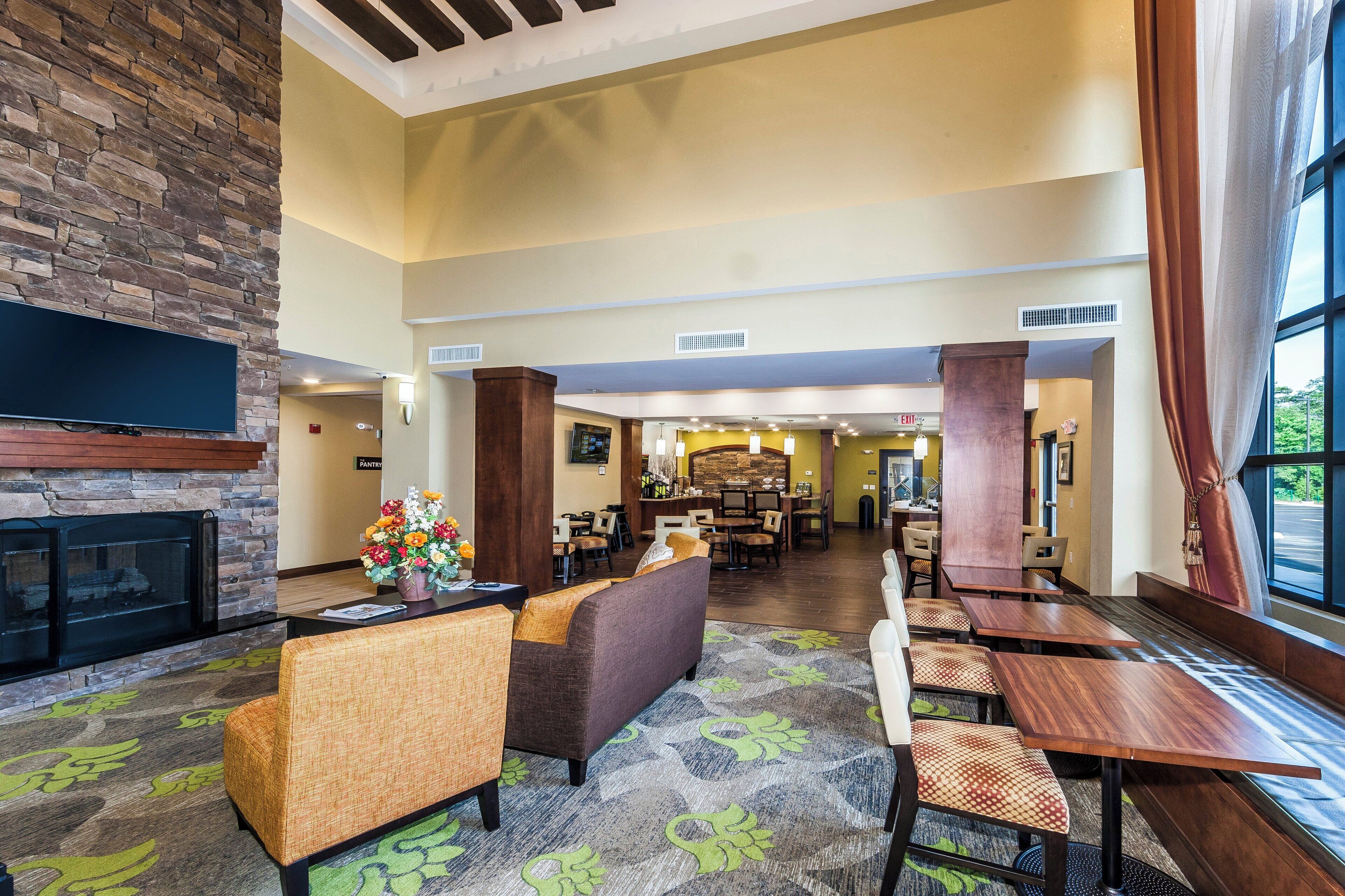 A hotel lobby with a fireplace, seating area, and a view of the outdoors.
