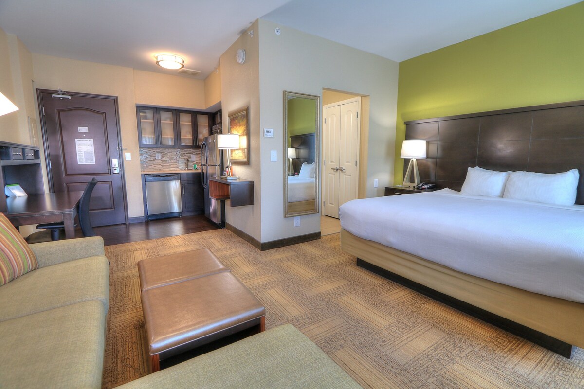Une chambre d’hôtel comprenant un lit, un canapé, un petit coin cuisine et une salle de bain.