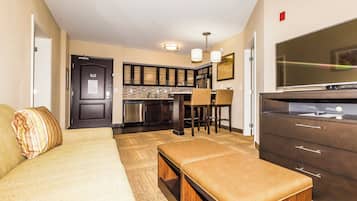 A compact living space with a kitchenette, a dining area, and a seating area with a sofa and ottoman.