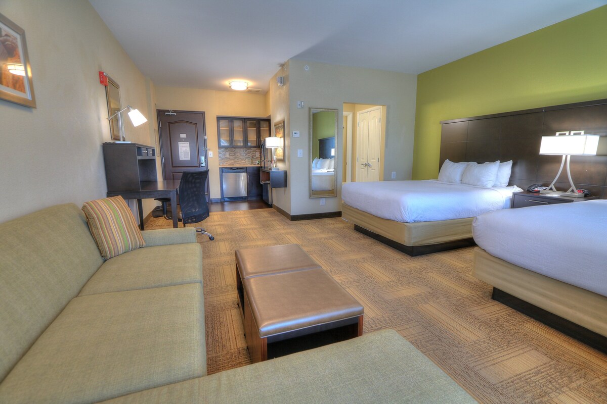 Une chambre d’hôtel avec un canapé, un lit, un bureau, une chaise et une petite table.