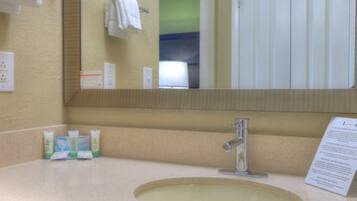A bathroom with a sink, mirror, towel rack, and toiletries.