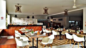 A restaurant with multiple tables and chairs, a bar area, and a checkered floor pattern.