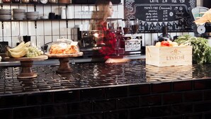 Una barra de café con un panel de menú, ollas colgantes y diversos alimentos exhibidos.