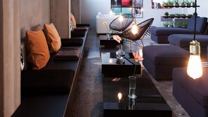 Un interior moderno con un largo banco, un sofá y una mesa de centro con un florero y velas.