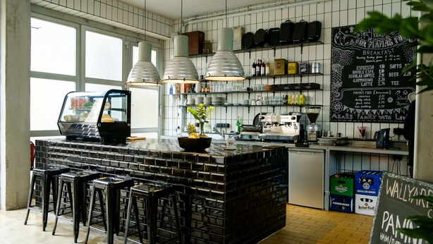 Una cocina moderna con una isla central, taburetes de bar y un menú en una pizarra.