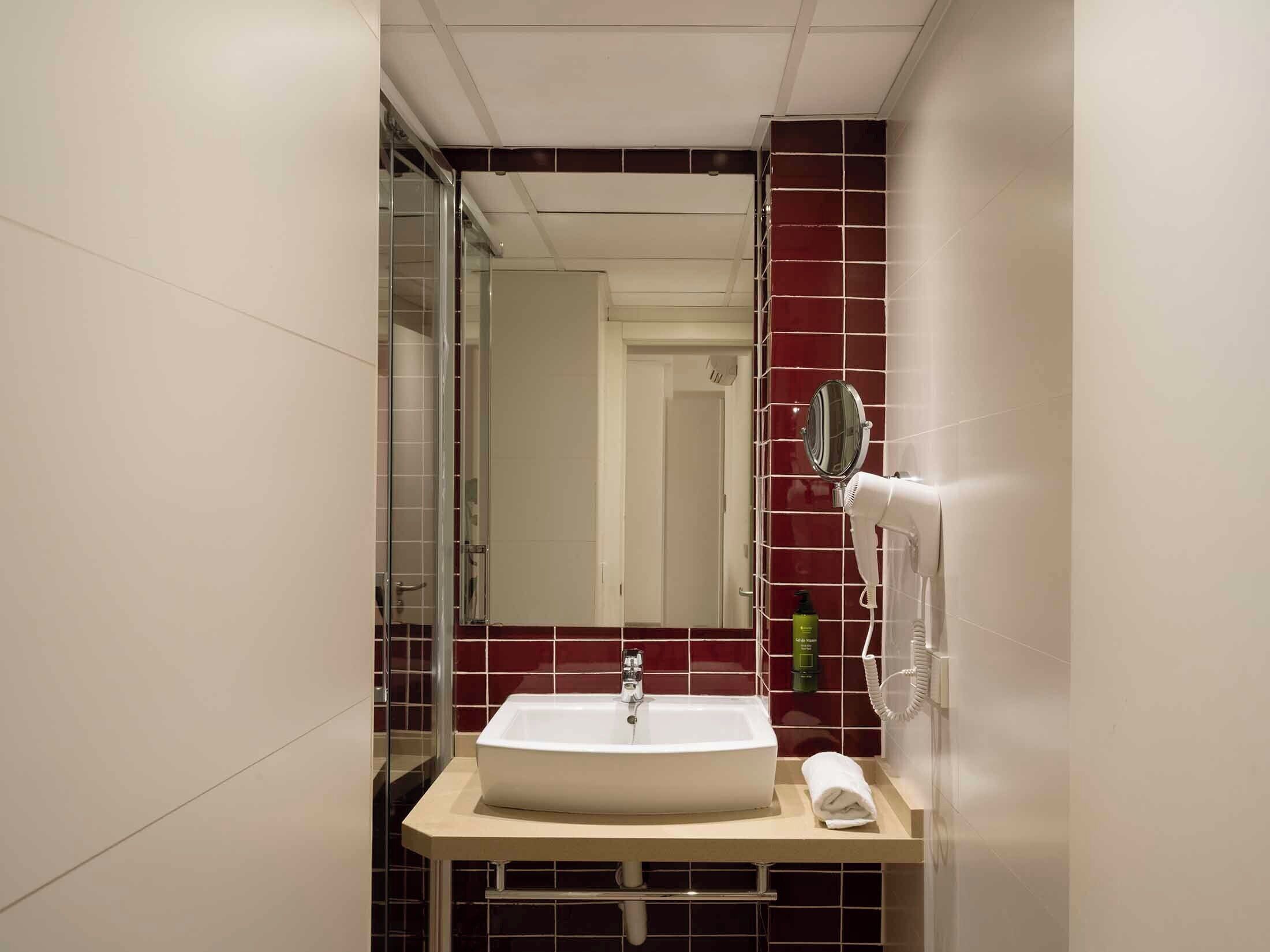 A bathroom with a white sink, a mirror, and a towel on the counter.