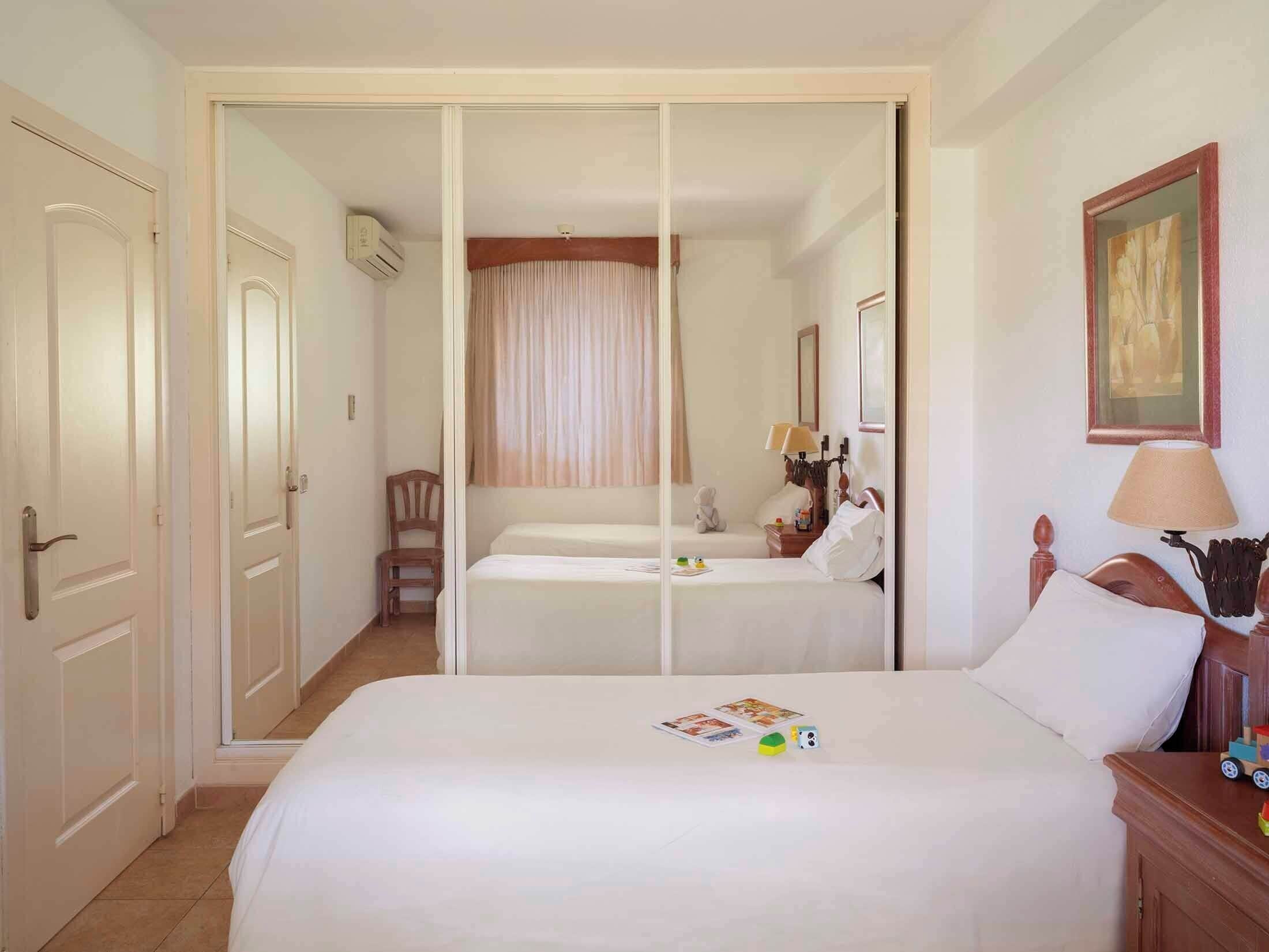 A hotel room with a large bed, a chair, a nightstand, and a painting on the wall.