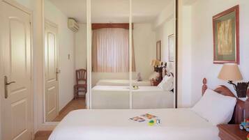 Een hotelkamer met een groot bed, een fauteuil, een nachtkastje en een schilderij aan de muur.