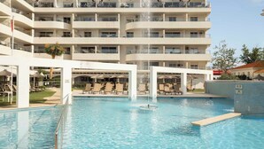 Una piscina al aire libre de temporada, sombrillas, tumbonas