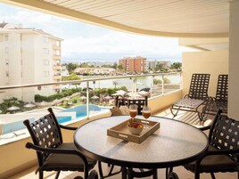 Un balcón con una mesa redonda, sillas y vistas a una piscina y edificios.