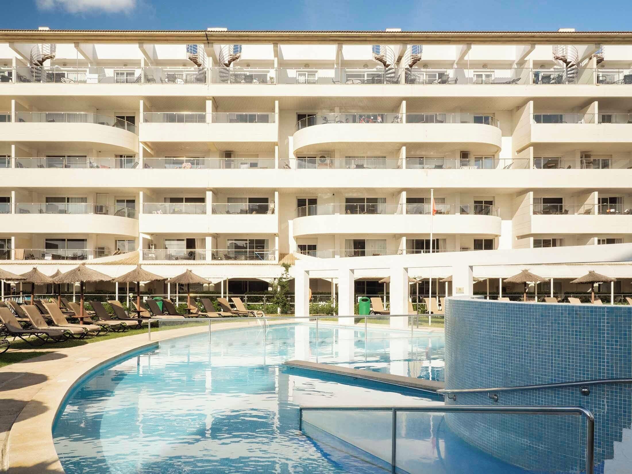 Una piscina al aire libre de temporada, sombrillas, tumbonas