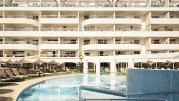 Una piscina al aire libre de temporada, sombrillas, tumbonas