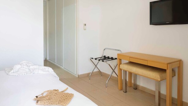 A bedroom with a bed, a desk, a chair, a TV, and an air conditioning unit. - Ona Garden Lago (Alcúdia)