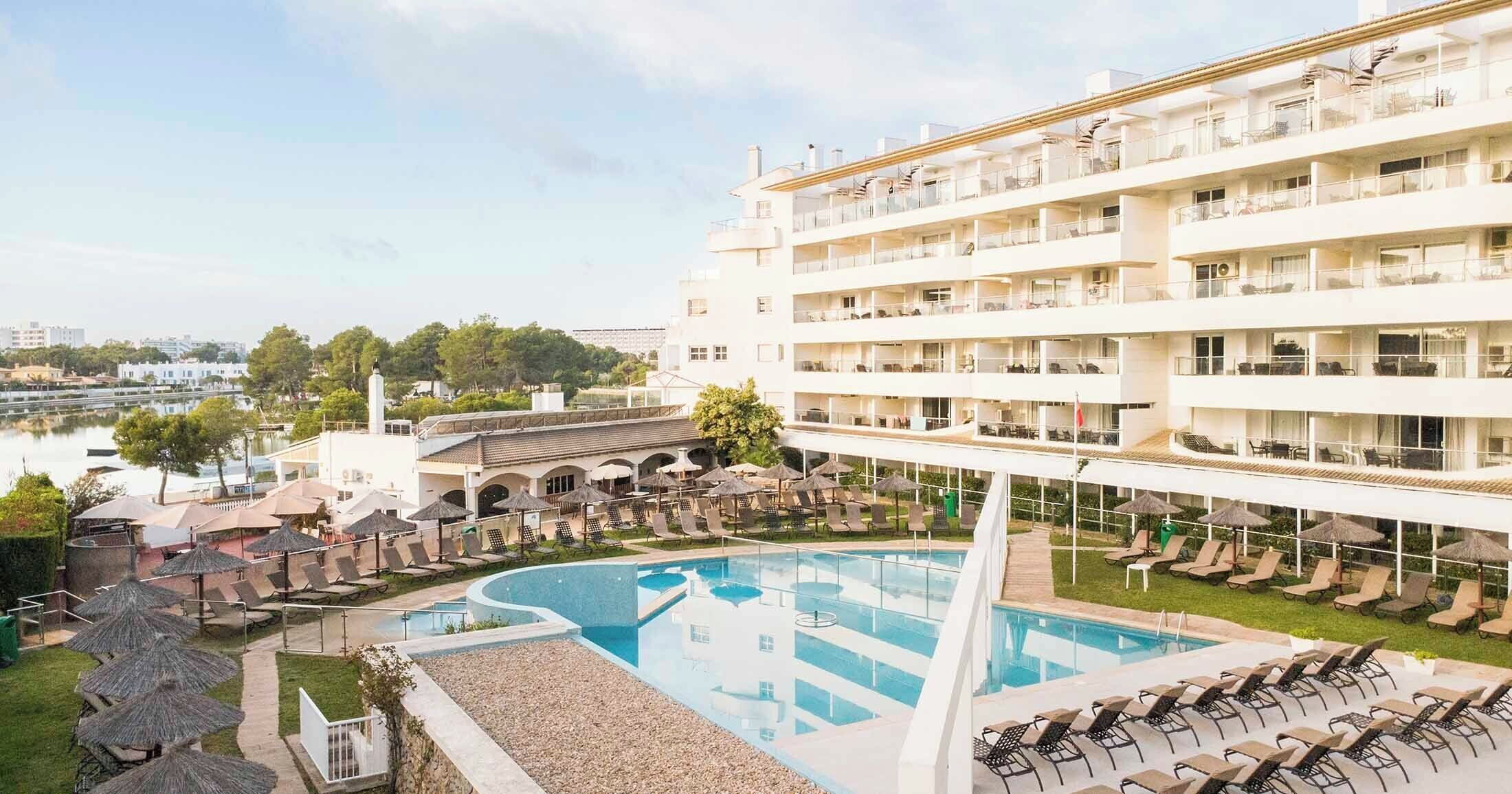 A hotel with a pool, lounge chairs, and a view of the city.