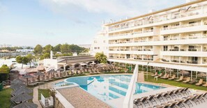 Un hotel con piscina, sillas de descanso y vistas a la ciudad.