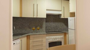 A compact kitchen with a built-in oven, a dishwasher, and a refrigerator. - Ona Garden Lago (Alcúdia)
