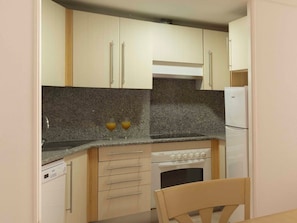 Una cocina compacta con horno integrado, lavavajillas y refrigerador.