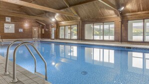 An indoor swimming pool with wooden walls and large windows. - The Kenmore Club (Aberfeldy)