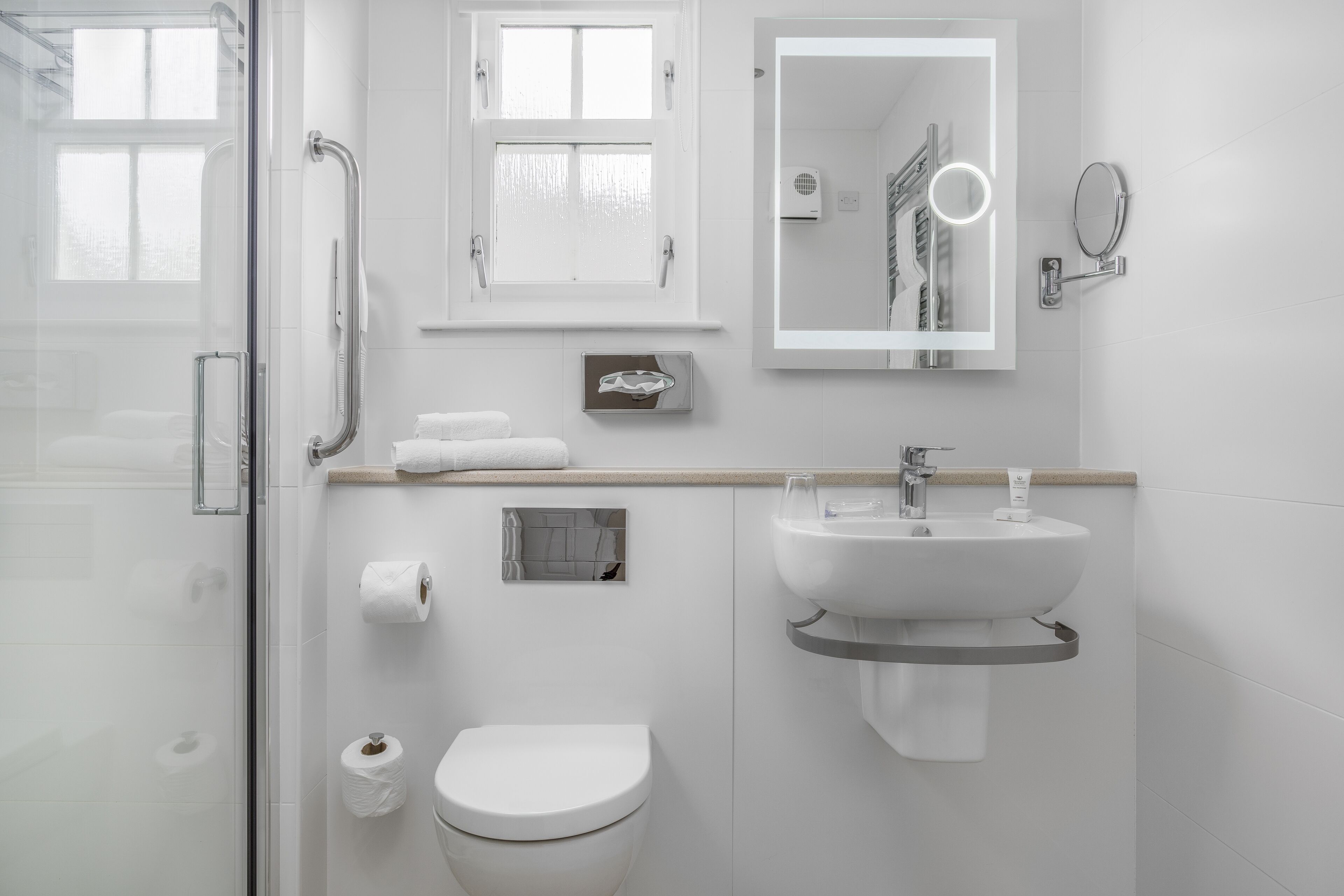 Une salle de bain moderne dotée d’une douche à parois de verre, de toilettes, d’un lavabo et d’un miroir.