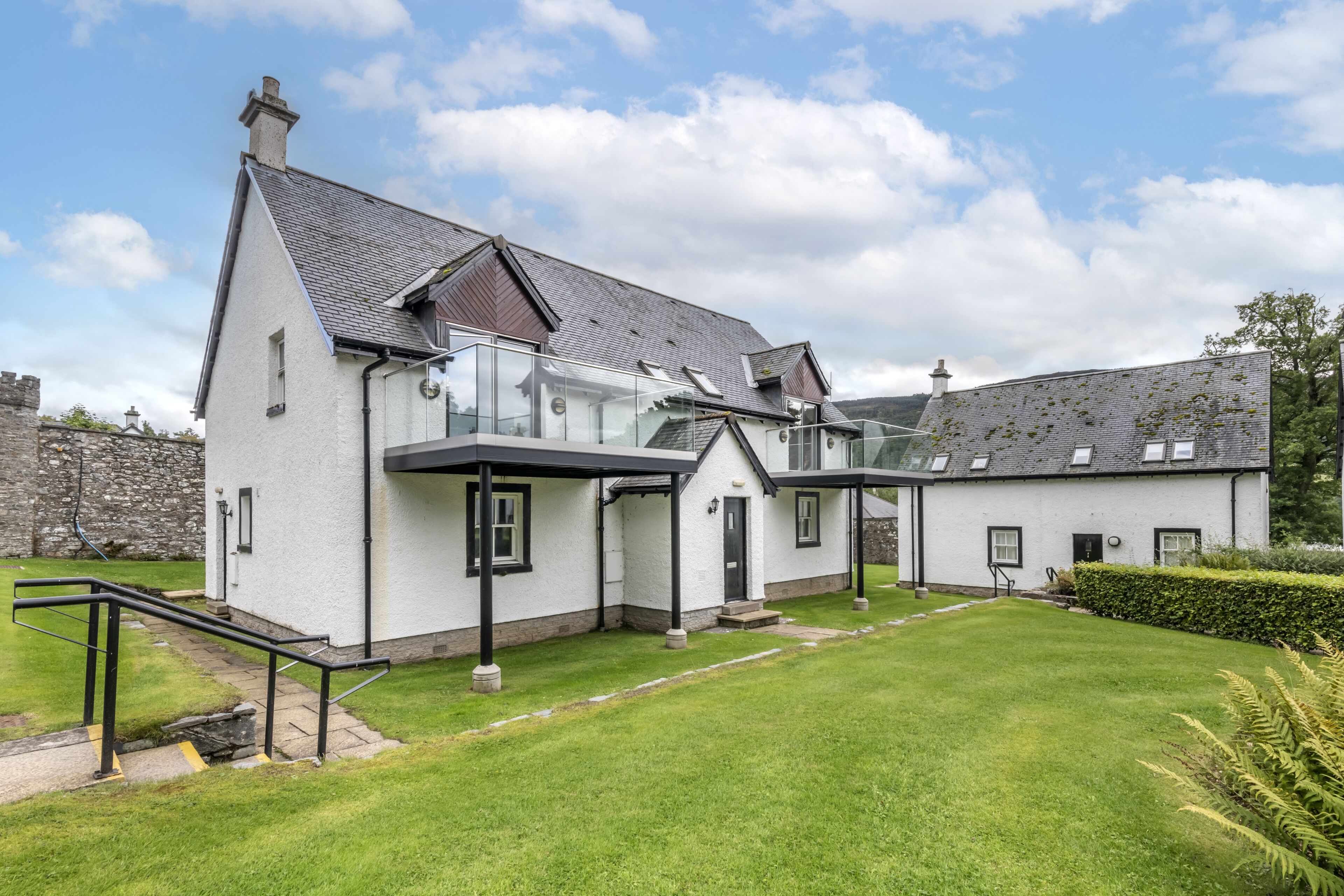 A modern two-story house with a sloped roof, large windows, and a well-maintained lawn.