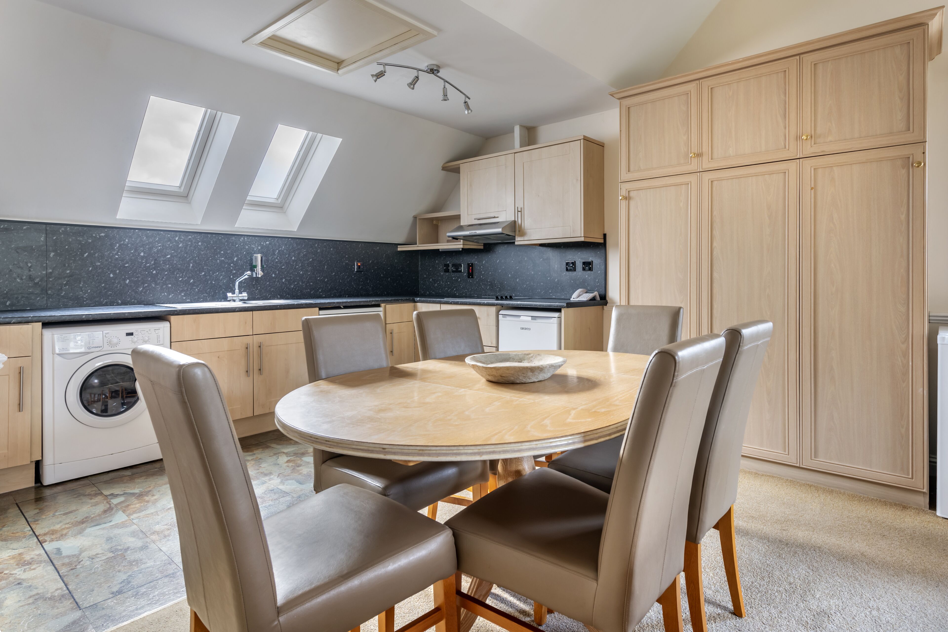 Una cocina moderna con una mesa de comedor redonda, electrodomésticos integrados y armarios de madera.