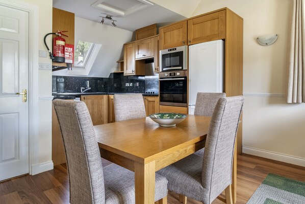 Una cocina compacta con armarios de madera, horno integrado y refrigerador.