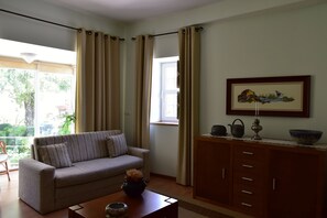 A living room with a sofa, a wooden cabinet, and a window with curtains.