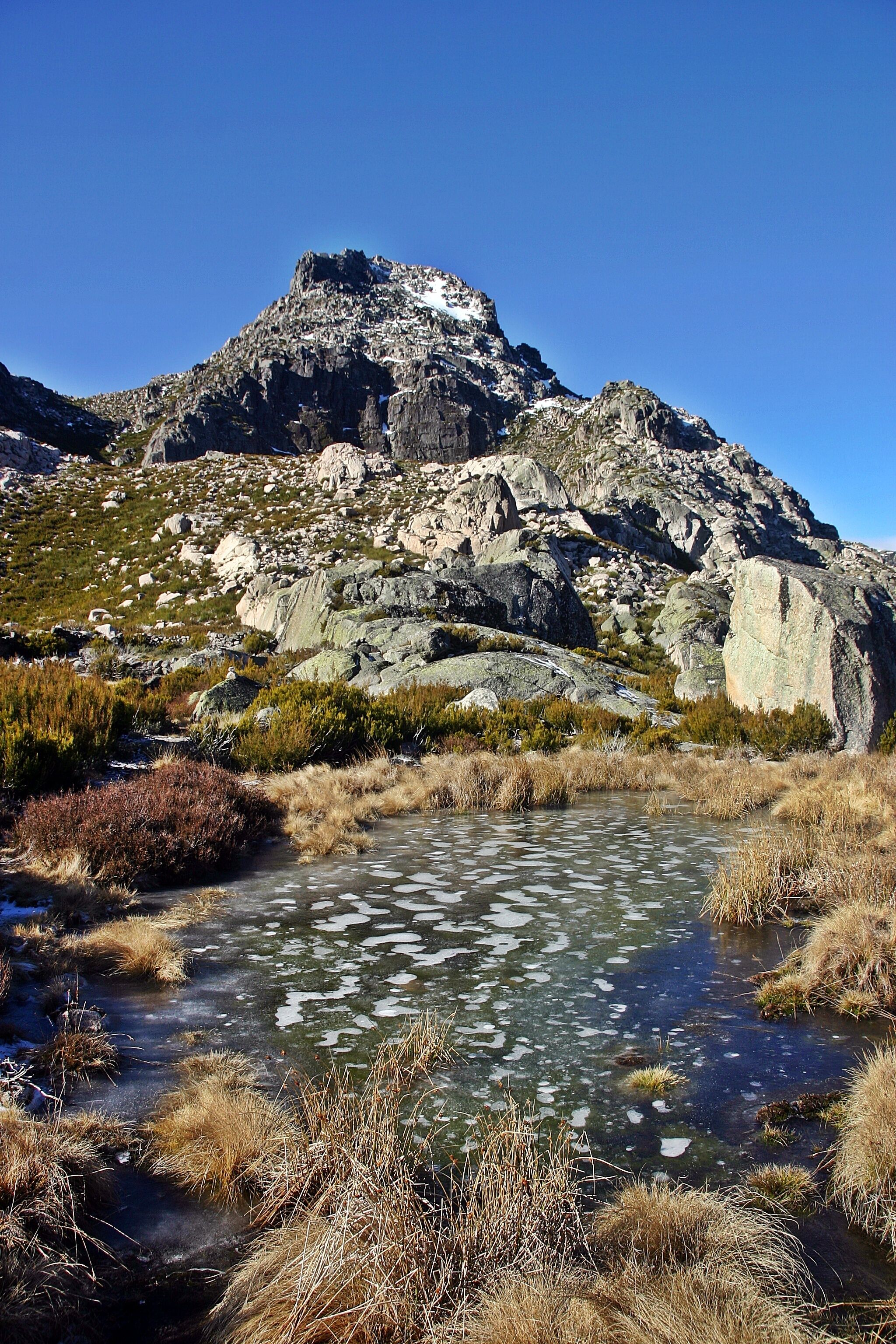 A mountainous landscape with a clear stream and rocky terrain.