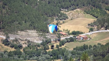 Bergachtig landschap met een luchtballon, een weg en verspreide gebouwen.