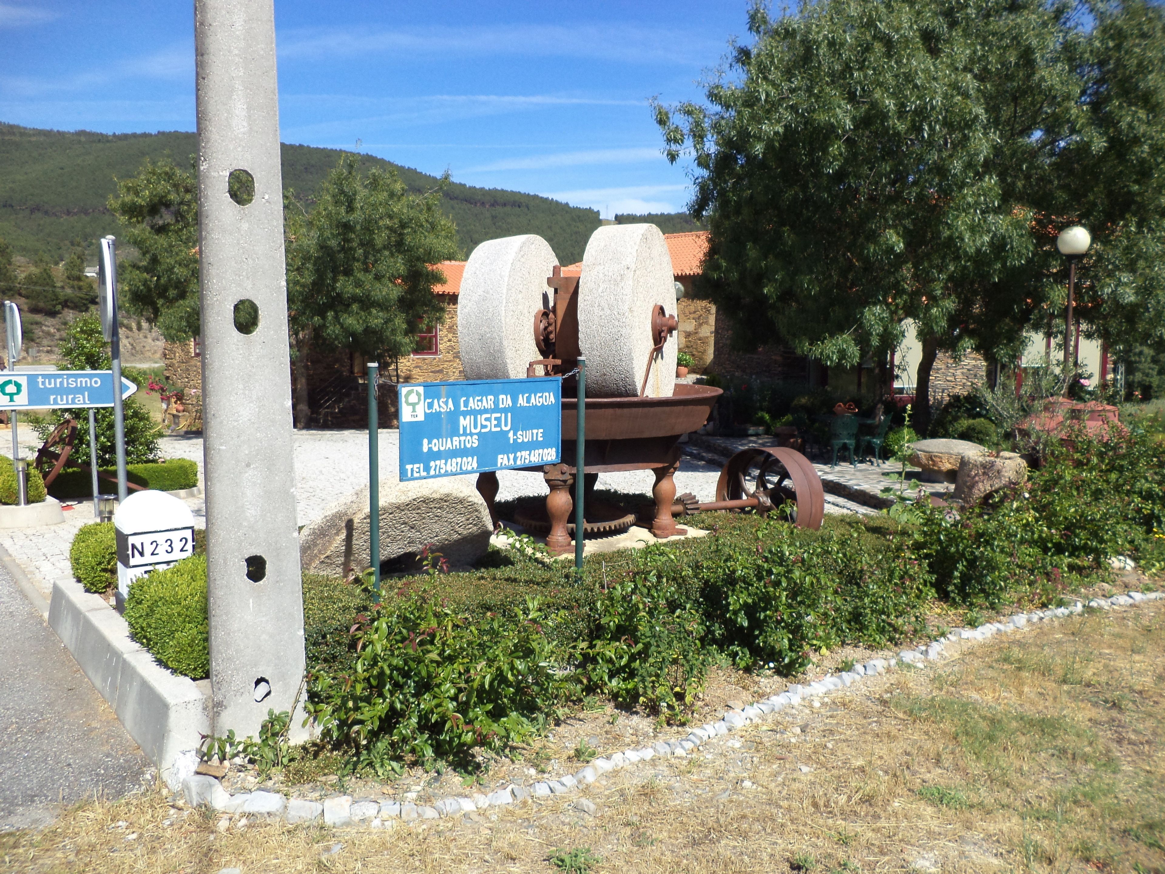 A rural tourism sign with a large stone structure, a telephone booth, and a stone path.