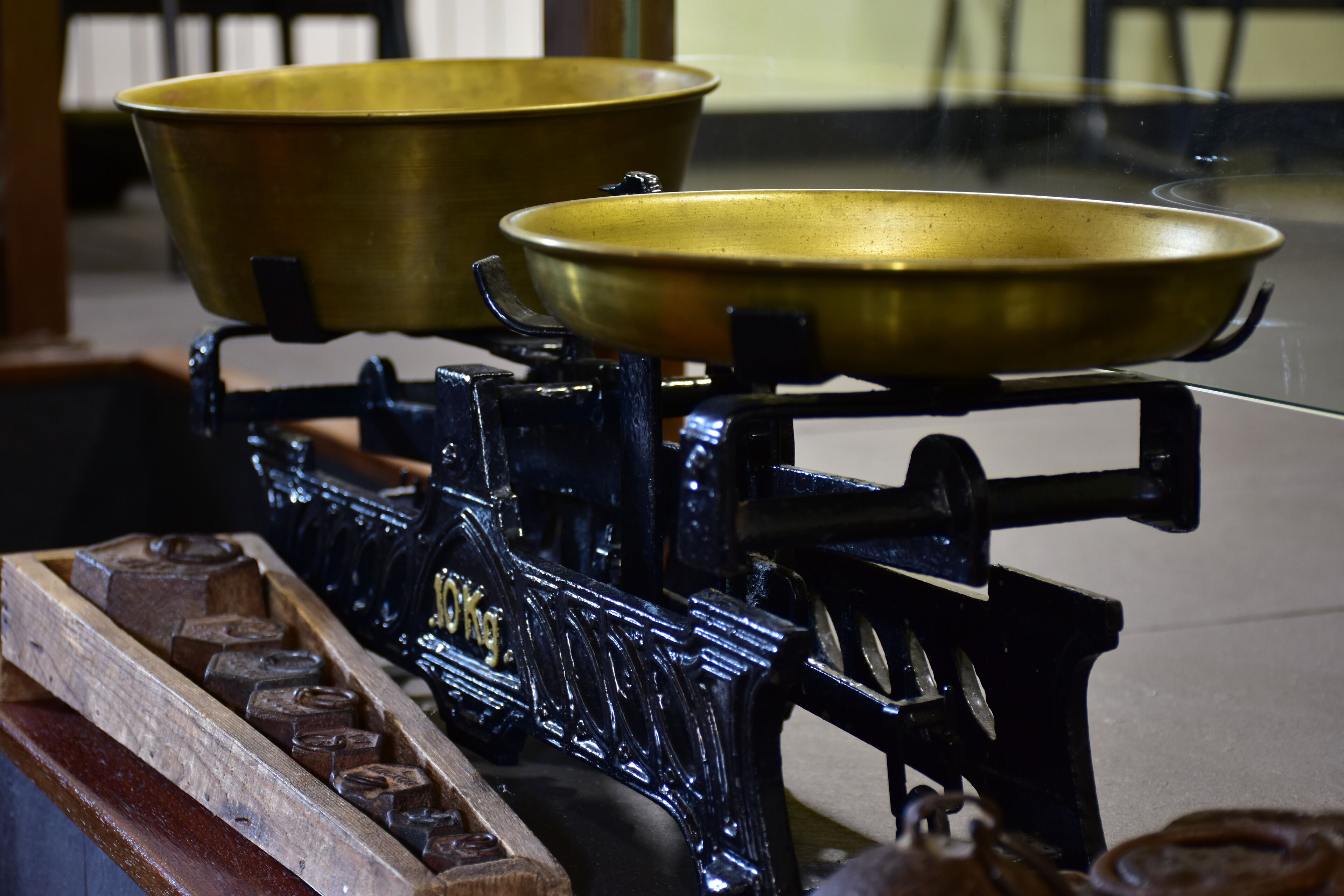 Una balanza de bronce con dos platillos sobre un soporte negro.