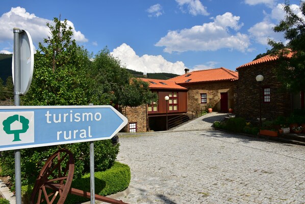 A rural tourism sign with a rustic stone building in the background.