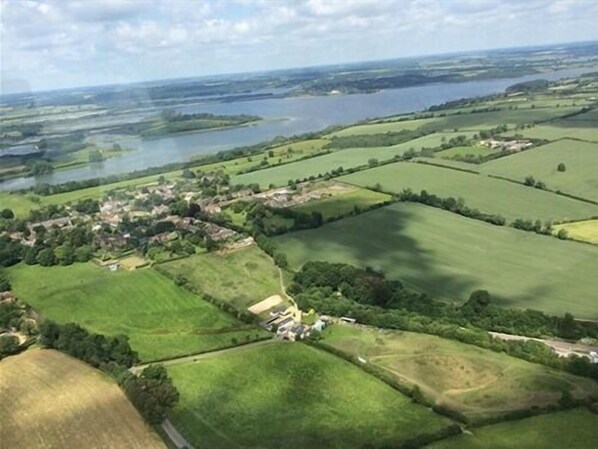 An aerial view of a rural area with fields, a small village, and a lake. - Broccoli Bottom (Oakham)