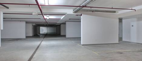 Un amplio estacionamiento vacío con pisos de concreto y paredes blancas.
