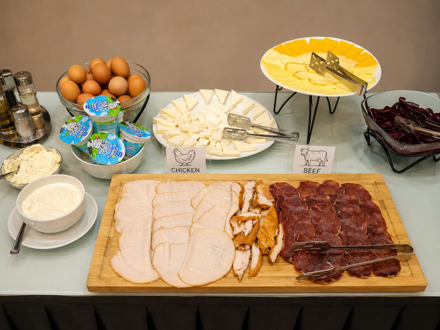 Una mesa de buffet con diversos alimentos, como huevos, queso y carnes.