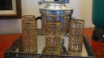 A tray with four glass tumblers and a silver pot on a red surface.