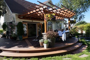 Eine Terrassenfläche mit Sitzgelegenheiten im Freien, Kübelpflanzen und einer Pergola.