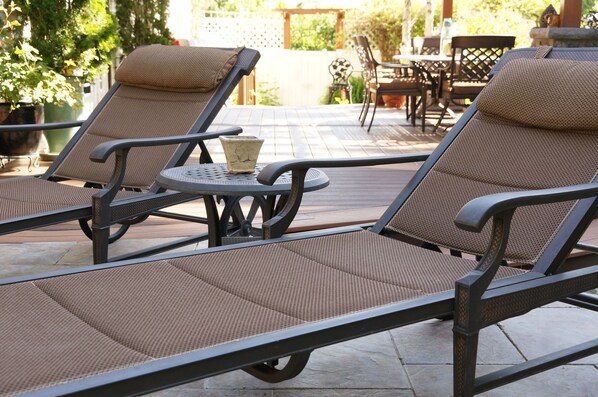A patio area with two reclining chairs, a small round table, and a potted plant. - R&R Guesthouse (The Dalles)