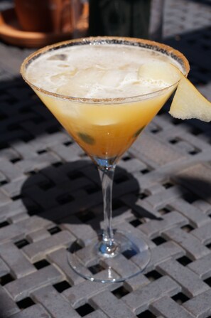 A cocktail in a martini glass with a lime wedge on the rim, placed on a metal table. - R&R Guesthouse (The Dalles)