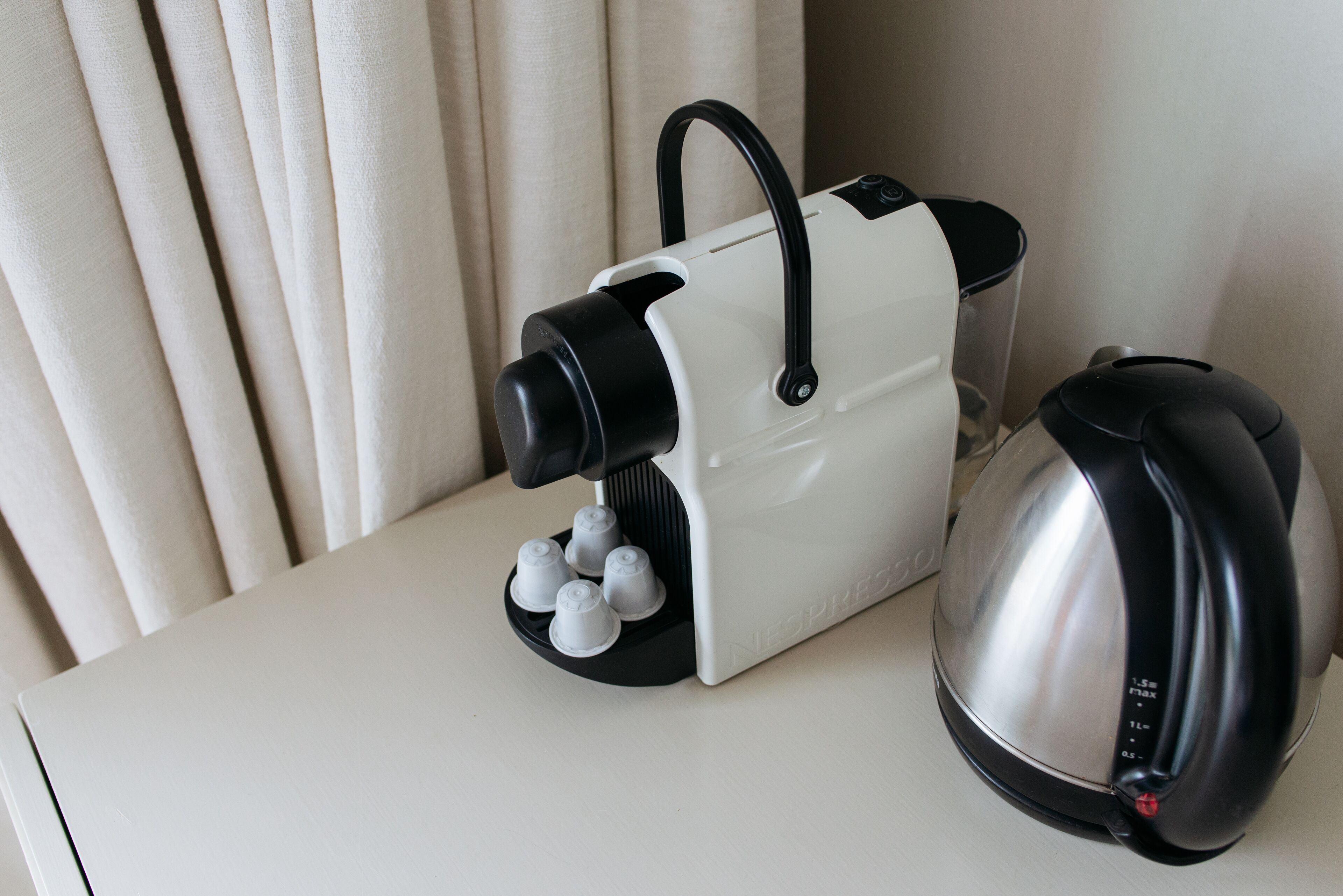 Eine Kaffeemaschine mit Wasserbehälter und ein Wasserkocher auf einem Tisch.
