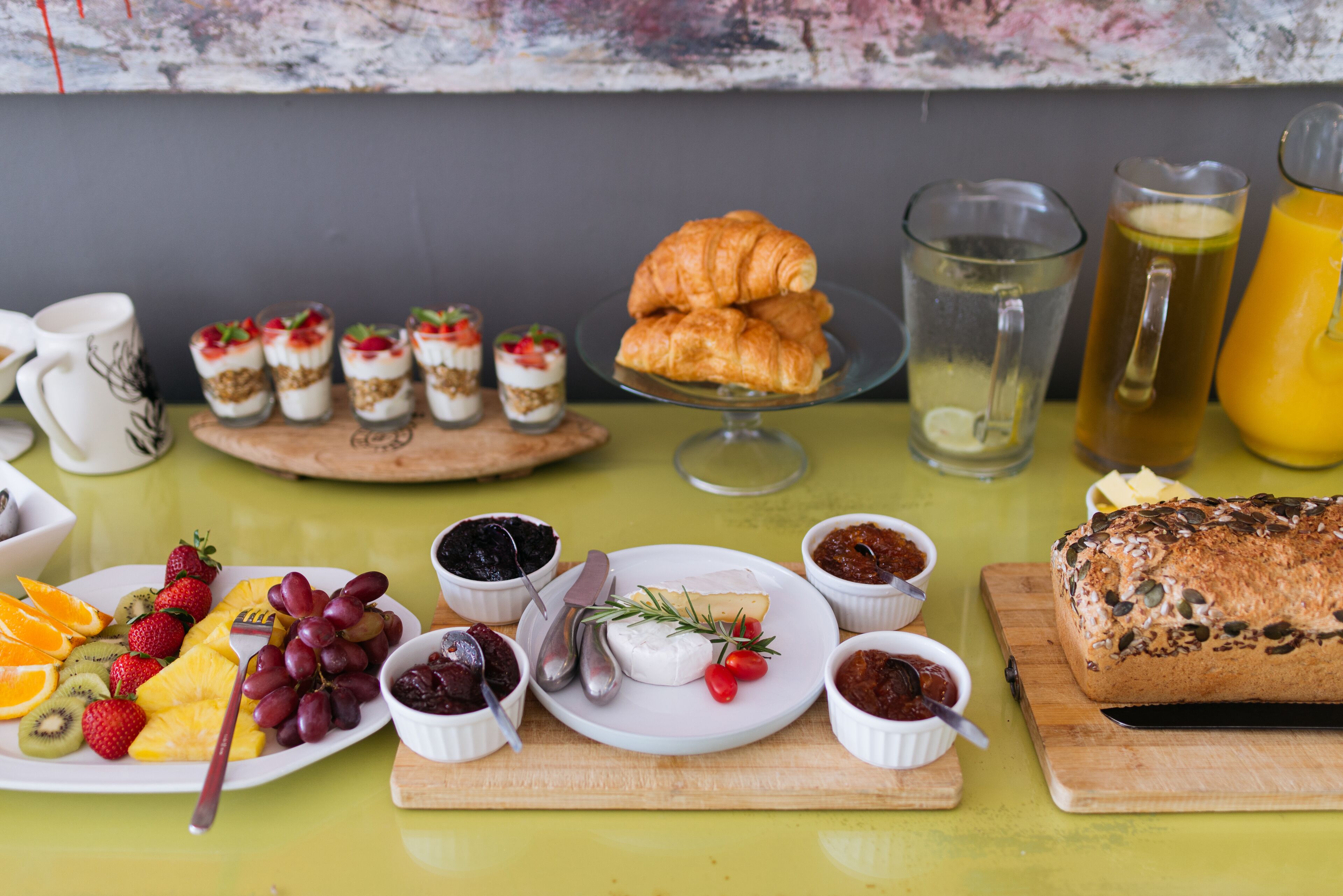 A breakfast table with various food items including fruits, pastries, and beverages.