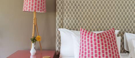 Une chambre d’hôtel avec un lit, une table de chevet avec une lampe et un vase rempli de fleurs.
