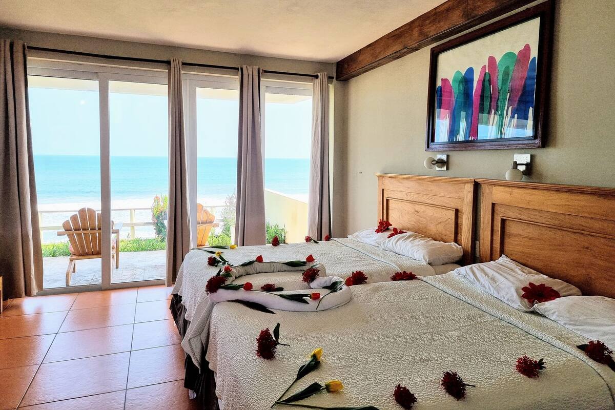 Quarto de hotel com uma cama grande, vista para o oceano e um quadro na parede.