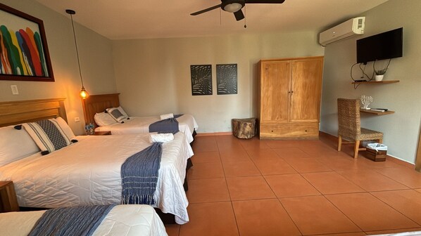 Habitación de hotel con una cama grande, un armario, un televisor y una pequeña mesa.
