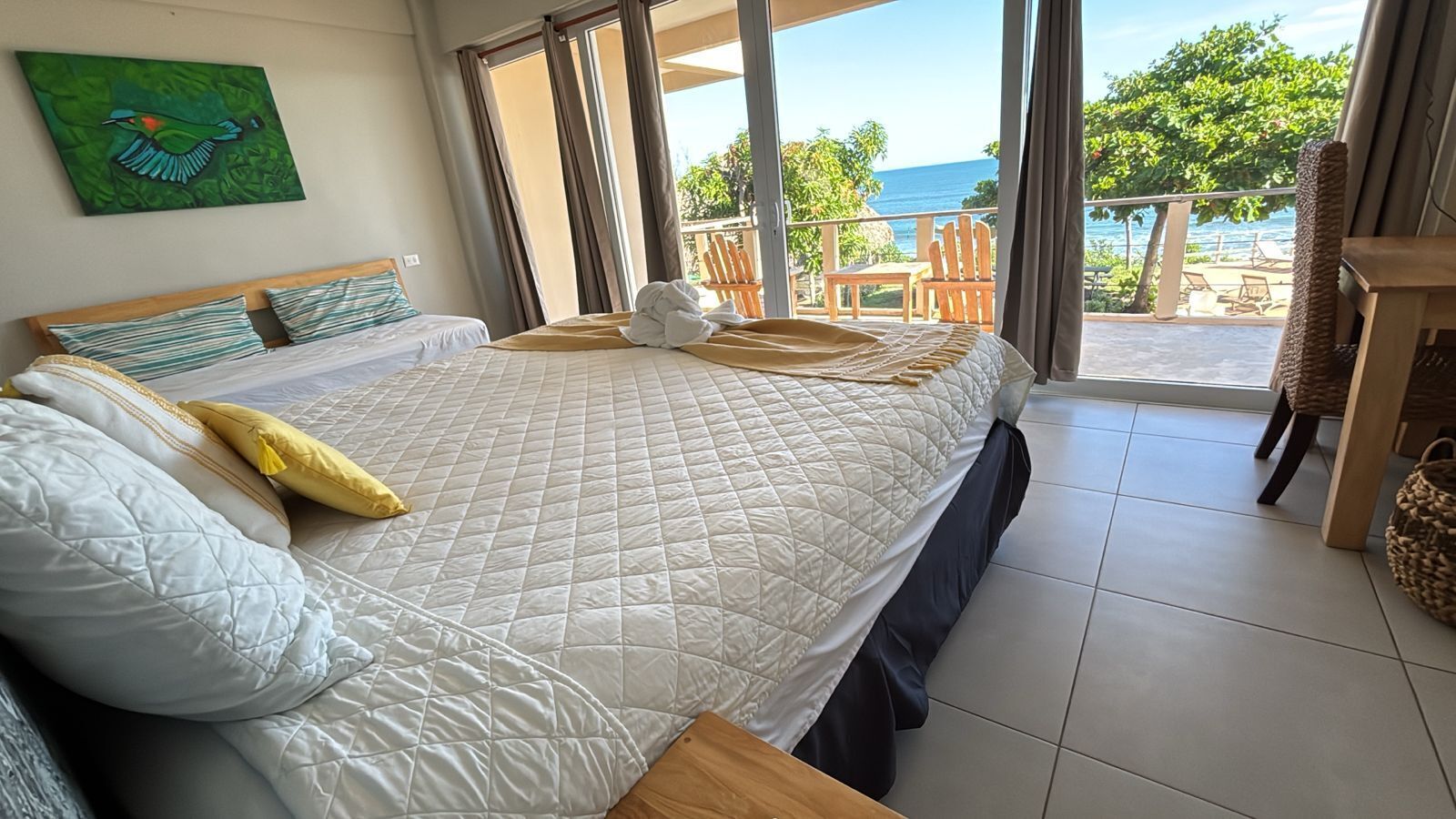 Ein Schlafzimmer mit einem Bett, Meerblick und einem Balkon mit Sitzgelegenheiten.
