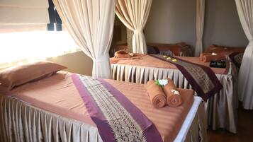 A room with two beds, each with a purple and gold bedspread, and a small table with a remote control.