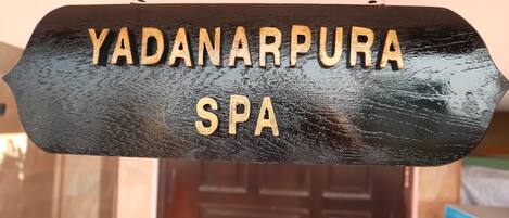 Un letrero negro con letras doradas que dice 'YADANARPURA SPA'.